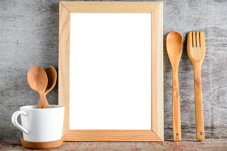 empty wooden frame and kitchen utensils on a wooden table. A layout for your design.の写真素材