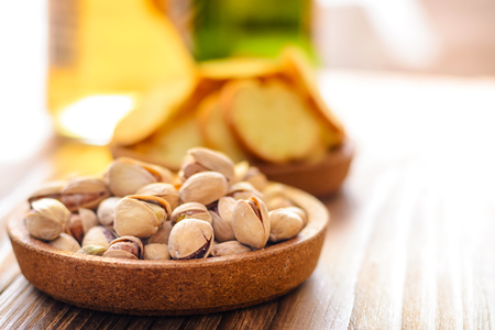 handful of salted pistachios close-up and beer in the background on a wooden tableの写真素材