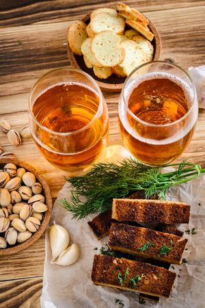 Two glasses of light beer, pistachios and croutons on a wooden table. Top viewの写真素材