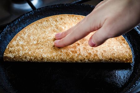 Young woman frying homemade quesadilla in a frying panの写真素材
