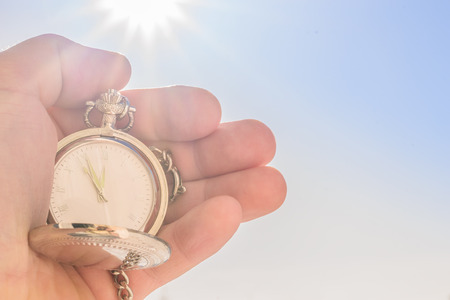 pocket watch in hand and blue sky in the sun. Photo with copy spaceの写真素材