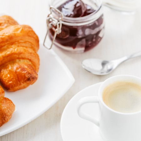 breakfast with cup of coffee and croissants with jam on white tableの写真素材