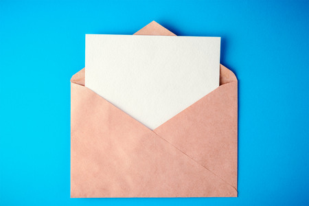 white paper card in an envelope on blue background with shadows, mockup. Top view flat lay