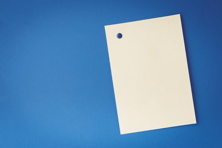 empty white sheet is pinned with a button on blue background. Layout for designの写真素材