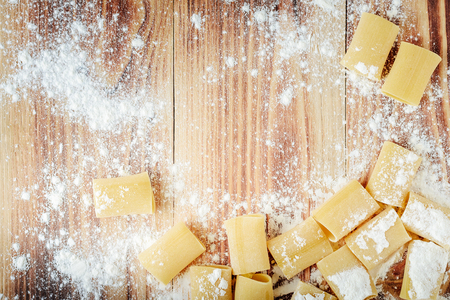 Italian pasta on a wooden background, sprinkled with flour. Photo with copy spaceの写真素材