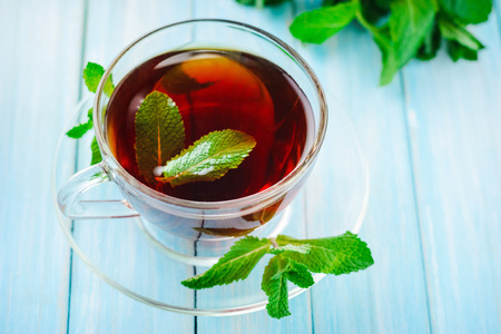 cup of black tea with fresh mint on blue wooden backgroundの写真素材