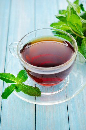 black tea and mint leaves in glass cup on blue backgroundの写真素材