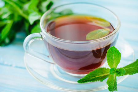 cup of black tea with fresh mint on blue wooden background, close upの写真素材