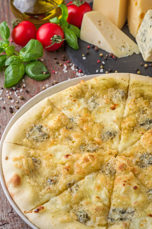 Italian pizza four cheese and ingredients on wooden tableの写真素材
