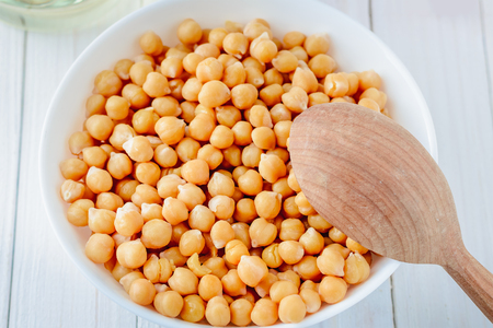coocked chickpeas in white dish with wooden spoon top viewの写真素材
