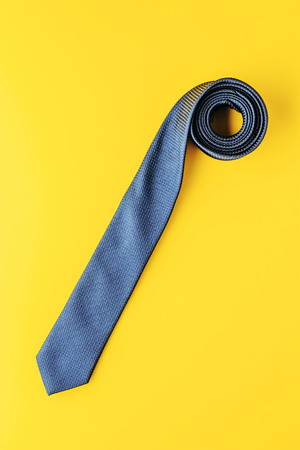 blue tie on yellow background top view, creative photographyの写真素材