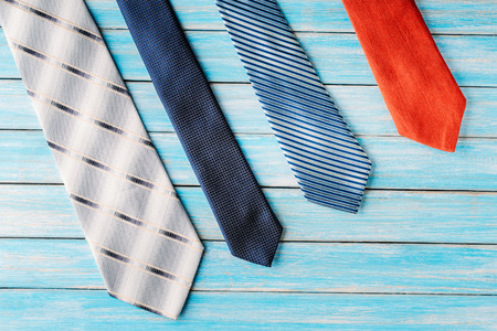 four different colored ties in row on wooden blue background. Top viewの写真素材