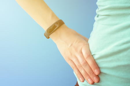 woman with fitness tracker on hand on blue background closeupの写真素材