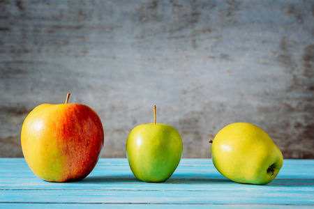 Three different apples on wooden table, close-up.の写真素材