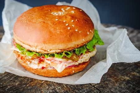 close up of appetizing homemade burger in wrapping paper on wooden tableの写真素材