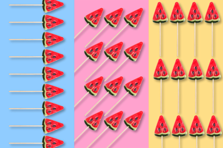 sweets in shape of watermelow on pastel blue, yellow and pink background. Minimal flat lay pattern