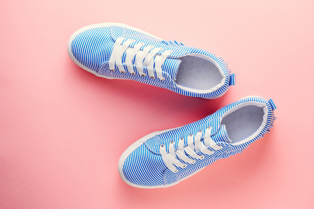 Blue striped female sneakers on pastel pink background. Flat lay, top view. Fashion blog conceptの写真素材