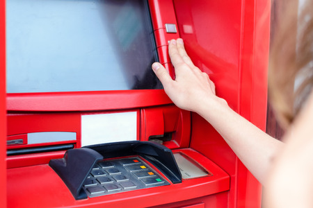 Young woman clicks buttons, making payment at ATM