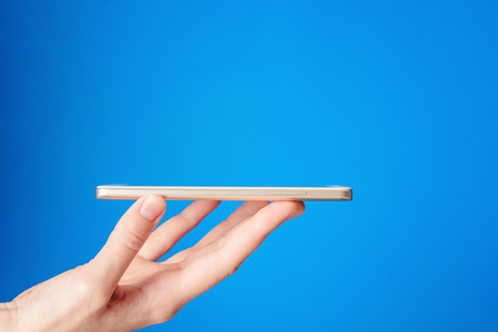 Woman hand hold smartphone on blue backgroundの写真素材