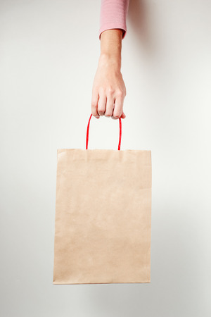 Close up of woman hand holding paper shopping bag close up, mockupの写真素材