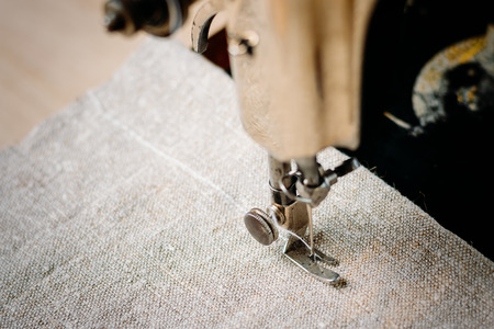 Part of vintage hand sewing machine and item of clothing. Steel needle with looper and presser foot...