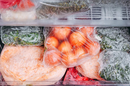 Different kind of deep frozen vegetables in plastic bags in refrigeratorの写真素材