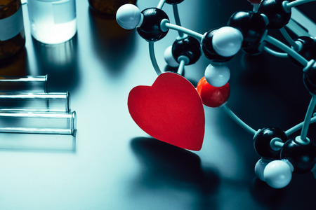Red paper heart and molecular structure model on black background. Love chemistry conceptの写真素材