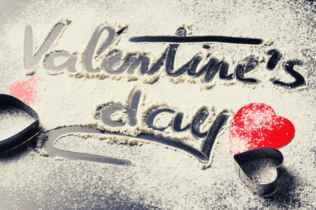 Words Valentines Day, written in flour and decorations from paper red hearts on dark background. Valentine's Day conceptの写真素材