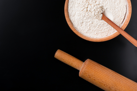 Bowl with wheat flour and rolling pin on dark background with copy spaceの写真素材