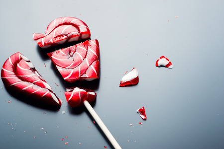 Broken lollipop in shape of heart on dark background with copy spaceの写真素材