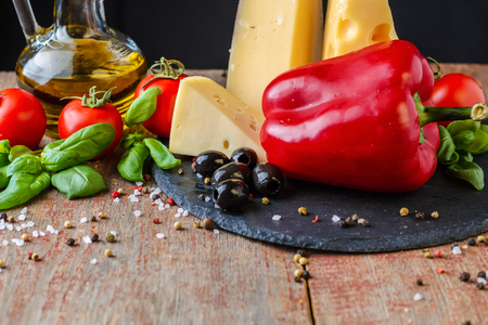 Different kind of cheese, tomato, pepper and olive oil on dark backgroundの写真素材