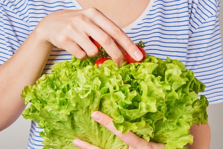 Woman hold bouquet of lettuce with cherry tomato in hands. Healthy nutrition conceptの写真素材