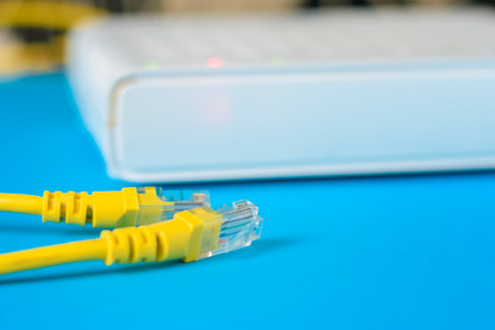 unplugged net cable and internet router on blue background