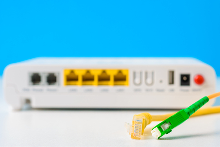 Fiber optical and network cables with internet wireless router on blue background