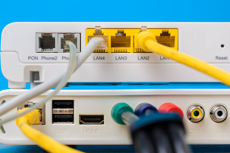 home wireless router with net cables plugged in on blue background, close up