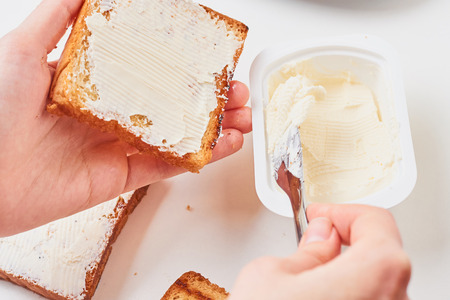 Woman hand make sandwich, spred toasted bread with cheese