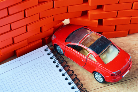 Car insurance concept. Red car crashed in brick wallの写真素材