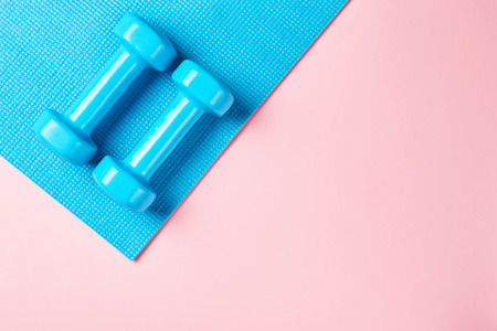 Fitnes minimalism concept. Dumbbells and sport bra on blue and pink backgroundm top viewの写真素材