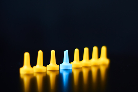 Individuality and leadership concept. Blue figure standing out from a yellow figuresの写真素材