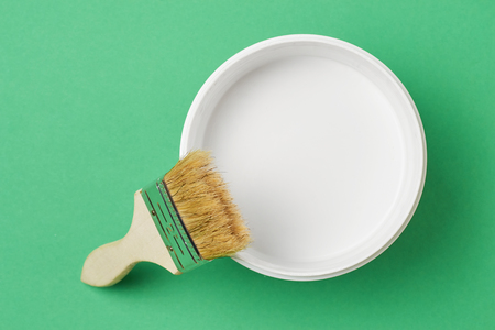 Brush and paint can with white color on green background, top viewの写真素材