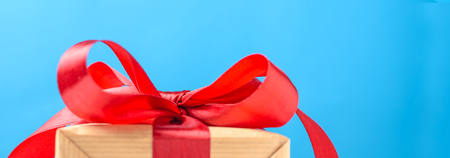 Gift box with red bow on blue background, bannerの写真素材