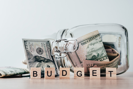 us dollars bill in glass jar and word budget made of wooden blocksの写真素材