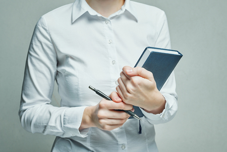 Business woman in white blouse with organizer diary in hands, close upの写真素材