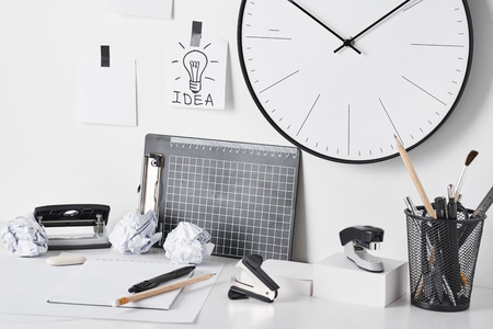 Office supplies, sticky notes and wall clock on white background, front view. Home workplace