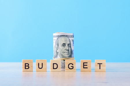 Rolled up dollar bills and word budget on blue background. Finance accounting concept