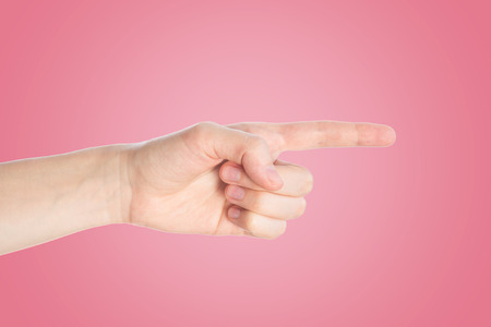 Pointing finger on pink background. Hand show direction gesture, close upの写真素材