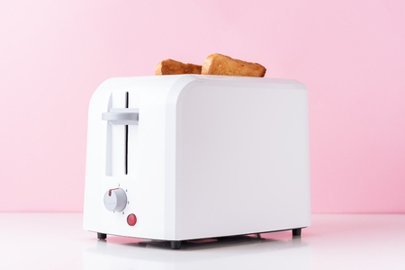 White toaster with  roasted toast bread on pink background, close up