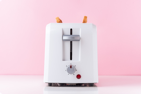 White toaster with  roasted toast bread on pink background, close upの写真素材