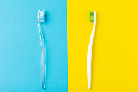 Two plastic toothbrushes on pastel blue and yellow  background, flat lay styleの写真素材