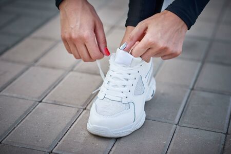 Woman get ready for run. Female hands tying shoelaces on sport sneakersの写真素材